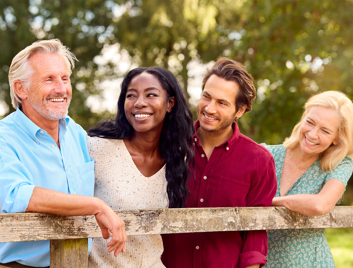Two couples standing near split rail fence smiling